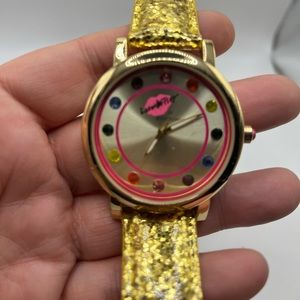 Betsey Johnson watch with a gold band.